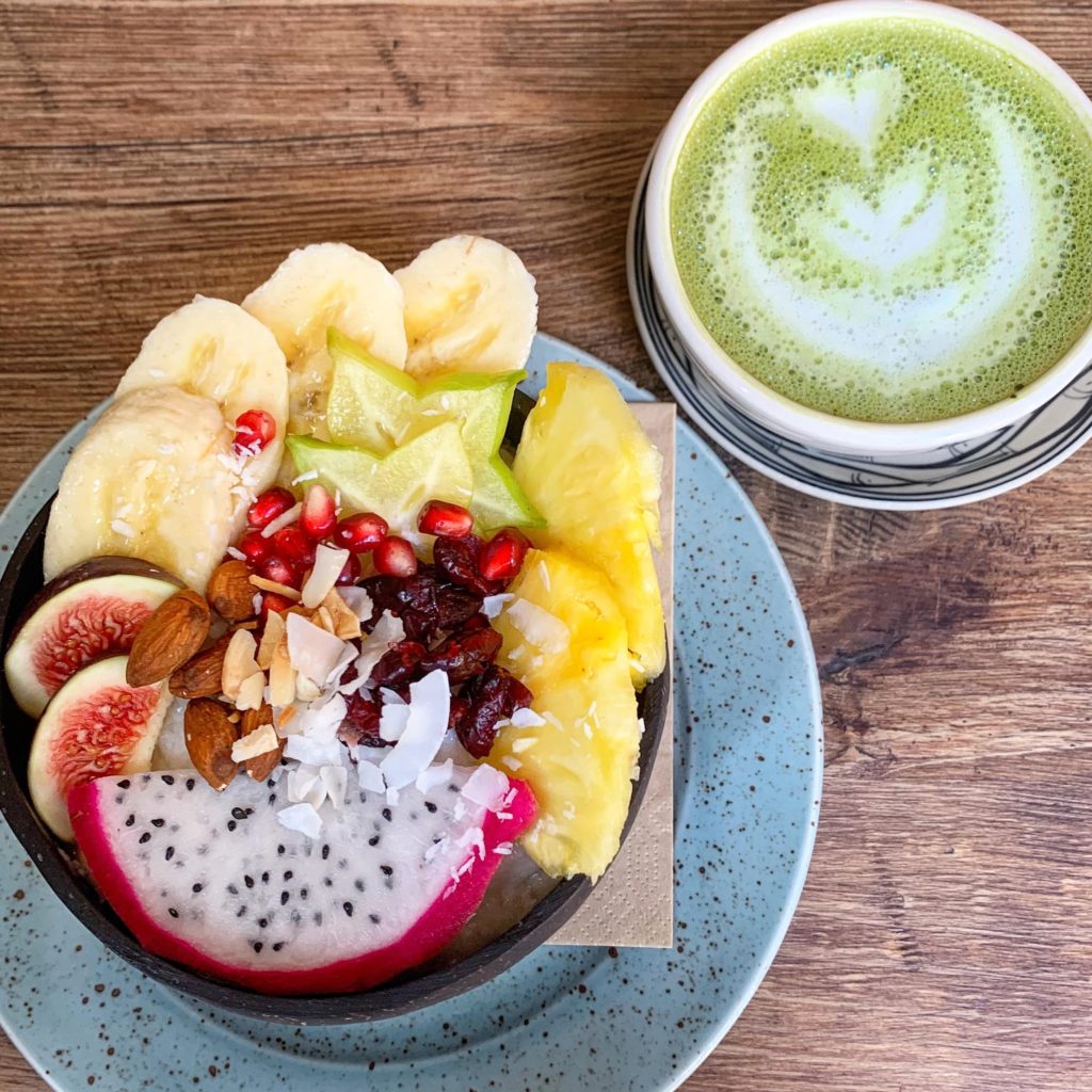Photo of a bowl of coconut rice with fruit and a matcha latte from Cafefin, one of the best vegan restaurants in Prague 