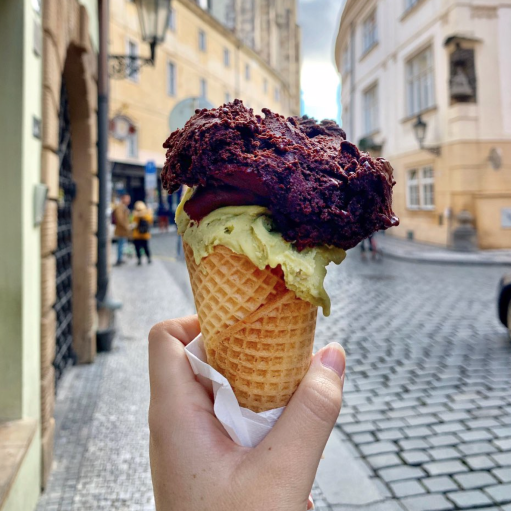 A photo of an ice cream cone with a pistachio scoop and a chocolate scoop on top from Creme De La Creme, one of the best vegan restaurants in Prague. 