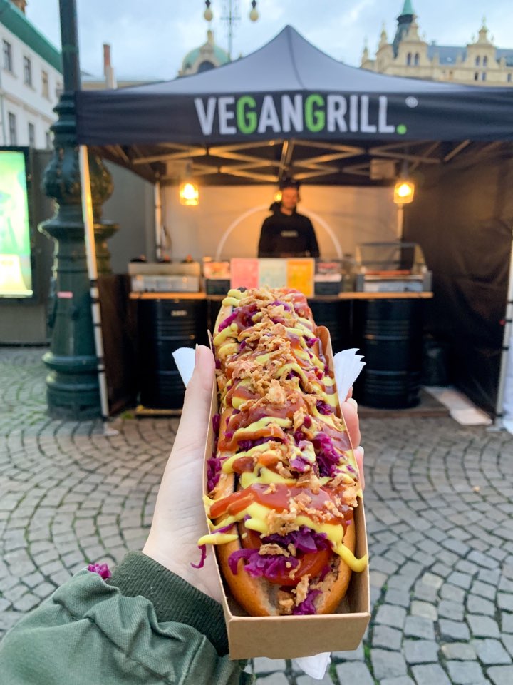 A photo of a vegan sausage with various toppings in front of the Vegan Grill, one of the best vegan restaurants in Prague  